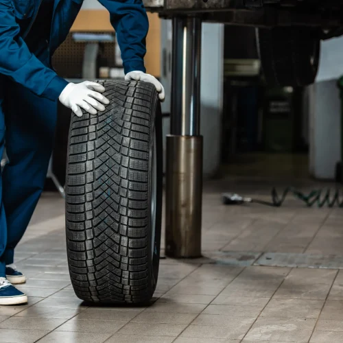 cropped-view-of-mechanic-with-car-wheel-in-worksho-2024-11-07-22-57-52-utc