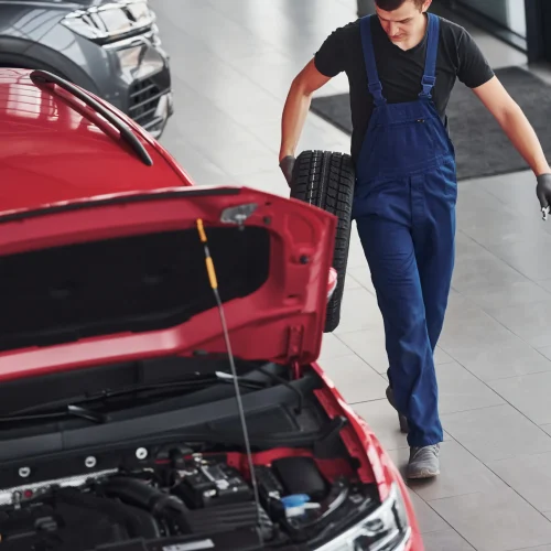 worker-in-black-and-blue-uniform-holds-car-wheel-a-2025-03-18-20-53-42-utc
